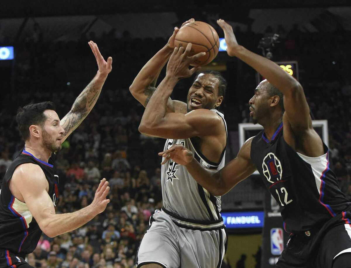 Kawhi Leonard of the SanAntonio Spurs, middle, drives toward the basket as J.J. Redick, left, and Luc Mbah a Moute (12) of the Los Angeles Clippers defend during first-half NBA action at the AT&T Center on April 8, 2017.