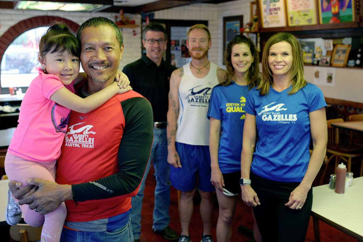 Popcorn Leonard, owner of The King and I restaurant, holds with his 3-year-old daughter Kaylee while standing with members of the West Texas Gazelles running club April 10, 2017, in his restaurant. Club members from foreground to background, Aliza Bowcutt, Ina Miller, Brian Younger, and Steve Berrones, will be competing in the Boston Marathon with Leonard. James Durbin/Reporter-Telegram