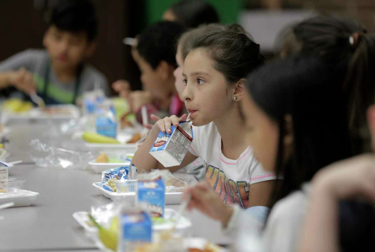 Fourth grader Mia Acuna drinks her milk with her classmatesat Hancock Elementary School eat lunch on Thursday, April 6, 2017, in Houston. The school offers a program where parents can put extra money in the funds so students who forget their lunch money get a full meal.