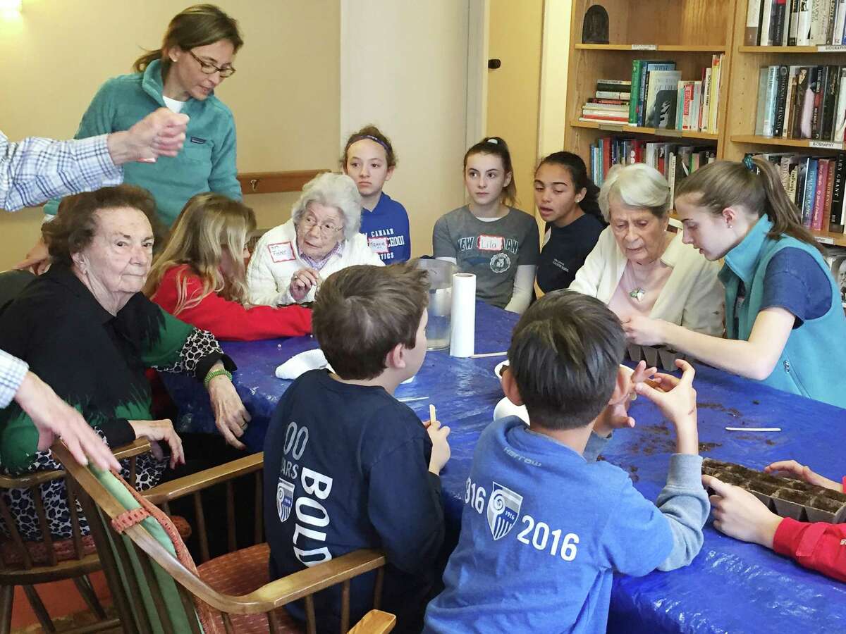 Students, their families and teachers from New Canaan Country School help seniors from Waveny Life Network?’s The Inn plant seedlings on April 1.