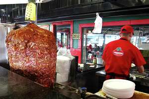 The massive al pastor trompo rotisserie at the counter of Taquitos West Ave.