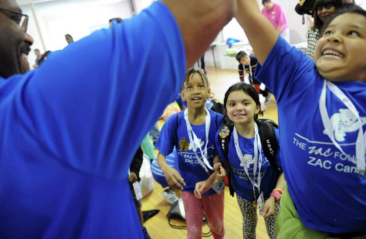 Third-graders Shaniah Euell, left, and Jailyn Bautista watch as Stephanie Alvarez high-fives Greenwich Boys & Girls Club CEO Bobby Walker Jr.during the ZAC Foundation swim camp closing ceremony at the Boys and Girls Club of Greenwich in Greenwich, Conn. Thursday, April 13, 2017. Children participated in the week-long ZAC Foundation swim camp at the Boys and Girls Club where they will spent time swimming in the pool while also learning important lessons about swimming safety. Karen and Brian Cohn founded The ZAC Foundation in 2008 in honor of their 6-year-old son, Zachary, who died after his arm became entrapped in a pool drain.