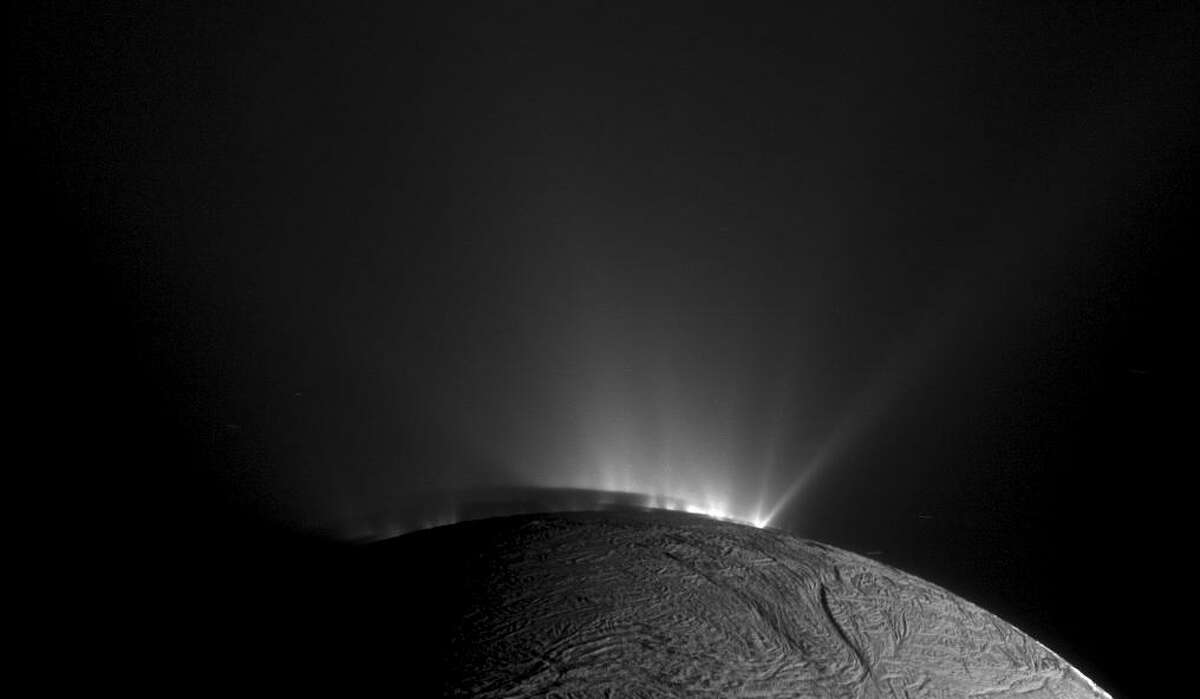 In an undated handout photo, rows of plumes rise from ice fractures on the surface of Enceladus, a moon orbiting Saturn. New findings from data collected by NASA?’s Cassini spacecraft suggest that icy moons like Enceladus could be the home to microbes or other life-forms. (NASA/JPL-Caltech/Space Science Institute via The New York Times) ?— FOR EDITORIAL USE ONLY