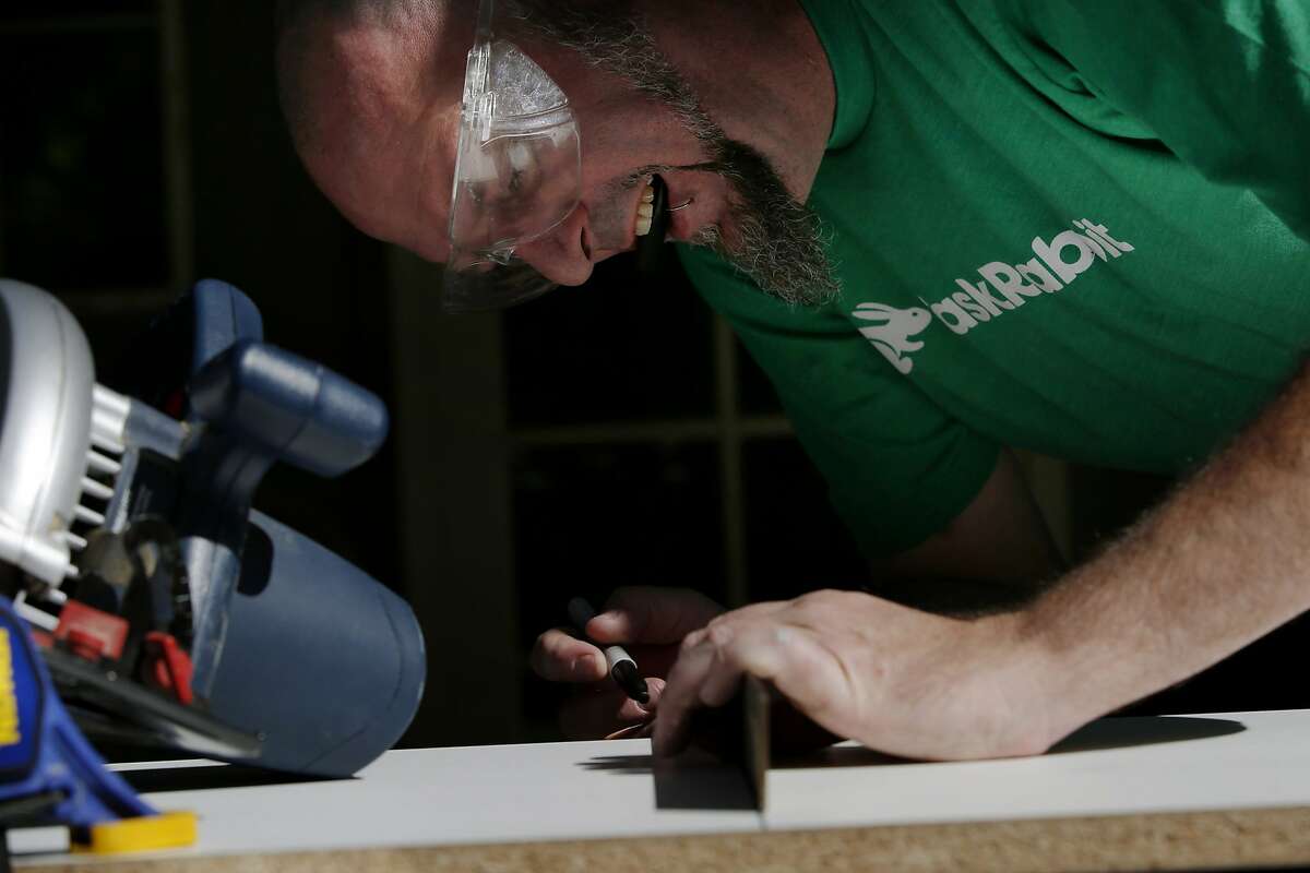 Duncan Cook marks wood to cut for a client's custom shelf on Thursday, April 13, 2017, in San Jose, Calif. Cook left his full-time job to become a task rabbit.