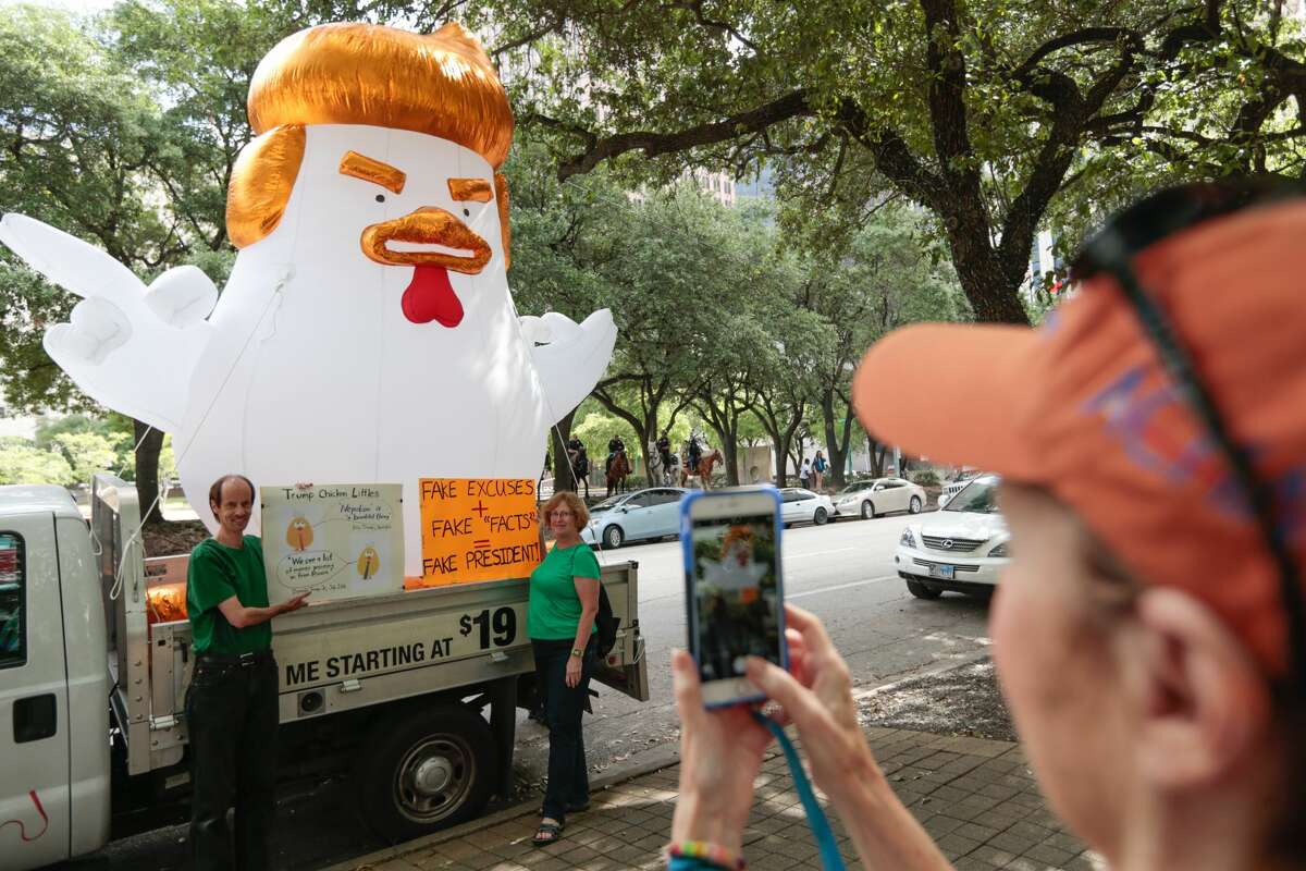 Jens and Melissa Moeller for a photo in front of an inflatable chicken shaped as President Donald Trump during a Tax March protest on Saturday, April 15, 2017, in Houston. (Brett Coomer / Houston Chronicle)
