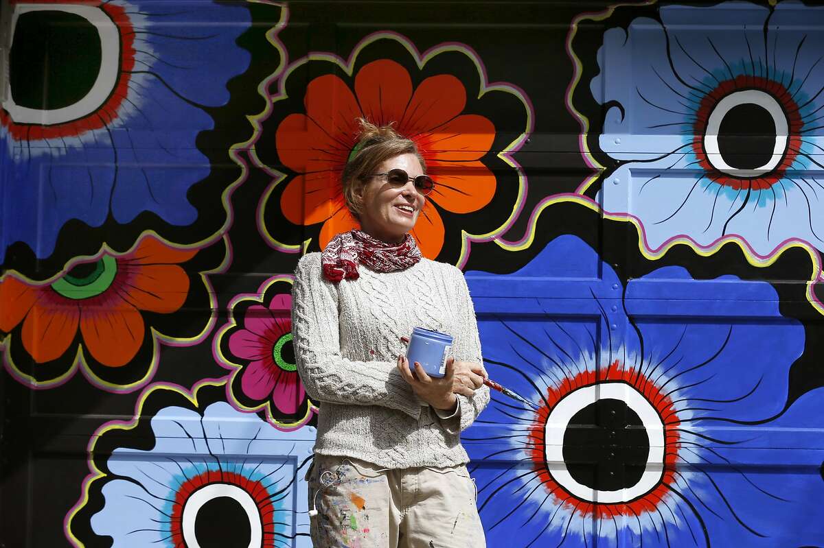 Muralist Megan Wilson paints a flower motif on a pair garage doors in the Haight Ashbury neighborhood of San Francisco, Calif. on Saturday, April 15, 2017. The Asian Art Museum commissioned Wilson to paint a series of floral murals throughout the city for its Flower Power exhibit to commemorate the 50th anniversary of the Summer of Love.