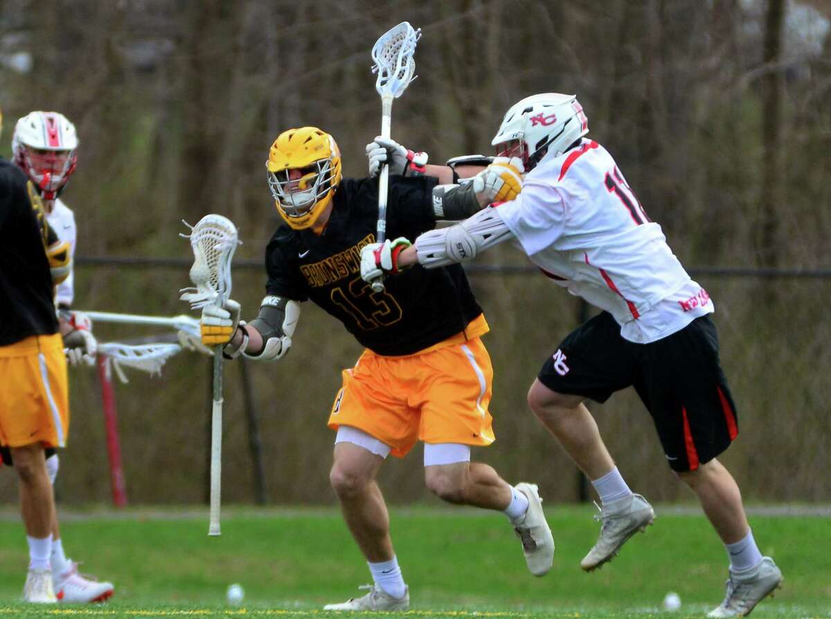 Brunswick’s Spencer Decker tries to fend off New Canaan’s Jack Hoelzer, right, during their game Saturday in New Canaan.