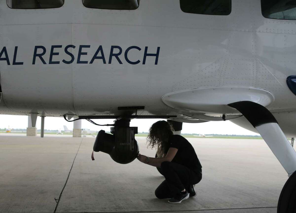 Amber Surrency, an aerial research photographer removes the hard drive from the camera on Co-Star's aerial research team's airplane on Friday, April 14, 2017, in Houston.