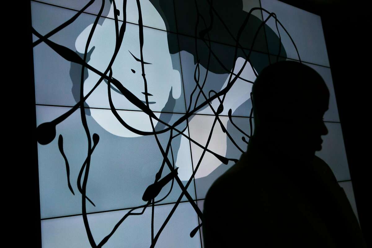 Receptionist, Lamont Chappell, is silhouetted against the new art display in the lobby of the Four Season Hotel in East Palo Alto, Calif. Friday, April 14, 2017.