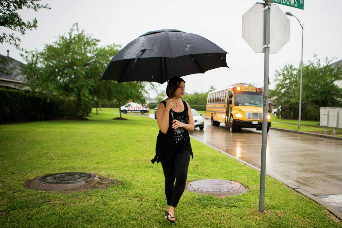 Rose Marie Escobar, 31, waits in the rain for the arrival of her son Walter Escobar, 7, from school, Tuesday, April 11, 2017, in Pearland. Her husband Jose Escobar used to be the parent that would pick up Walter, but that was before he was deported to El Salvador.