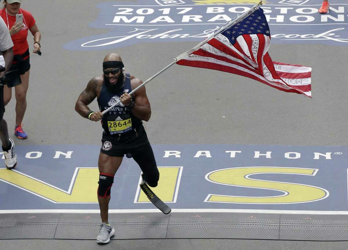 Jose Sanchez, of San Antonio, carries the United States flag across the finish line in the 121st Boston Marathon on Monday in Boston.
