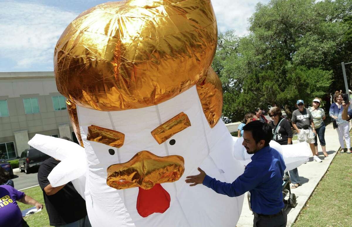 A Donald Chicken balloon figure in inflated as more than 100 protestors marched to Congressman Will Hurd's office on Rogers Ranch Road on Tuesday, April 18, 2017, pushing for the release of President Trump's taxes.