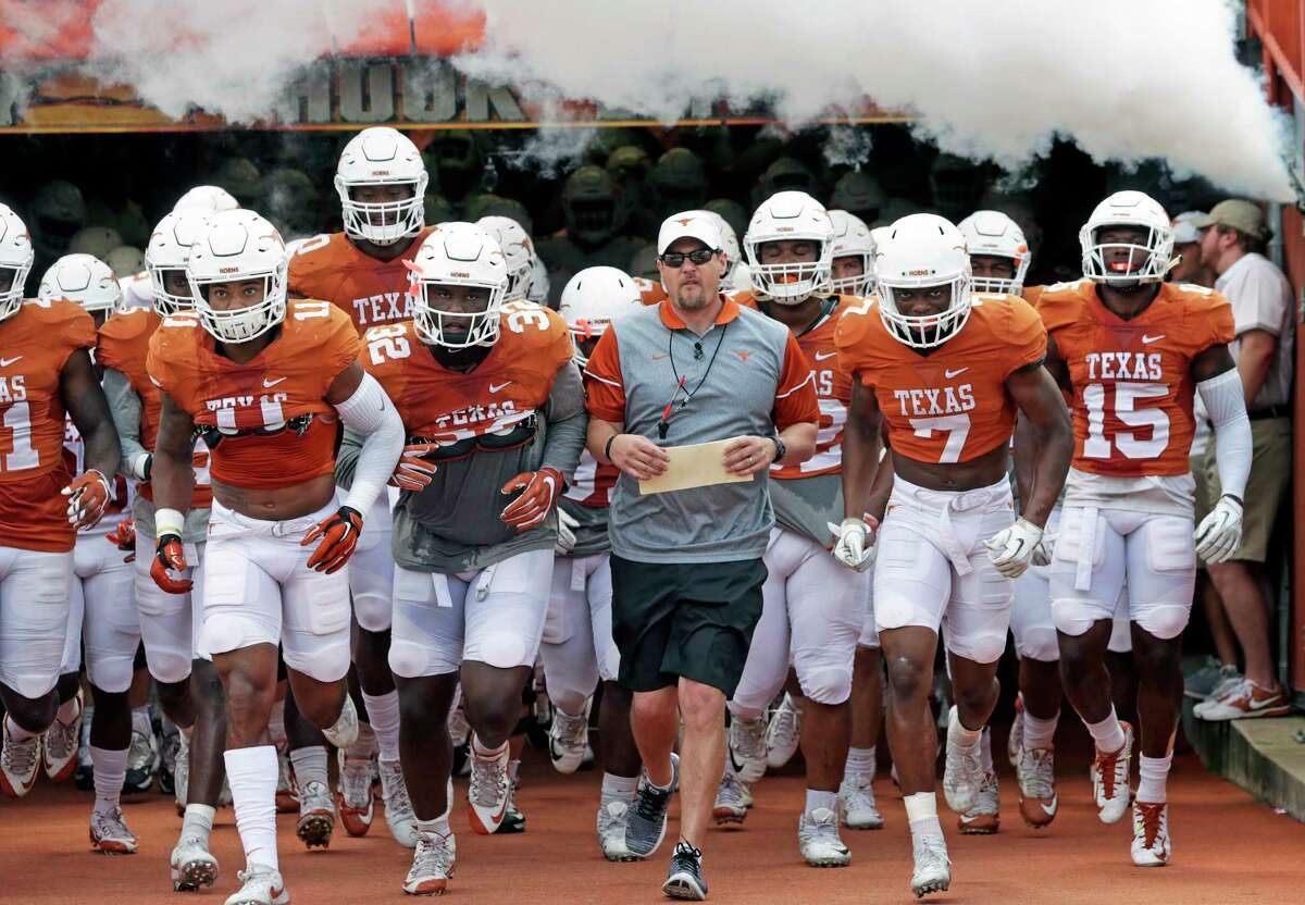 Trying to mange more than 100 players, coaches like Texas' Tom Herman, center, see the benefit of an additional assistant coach in providing guidance on and off the field for the large roster.