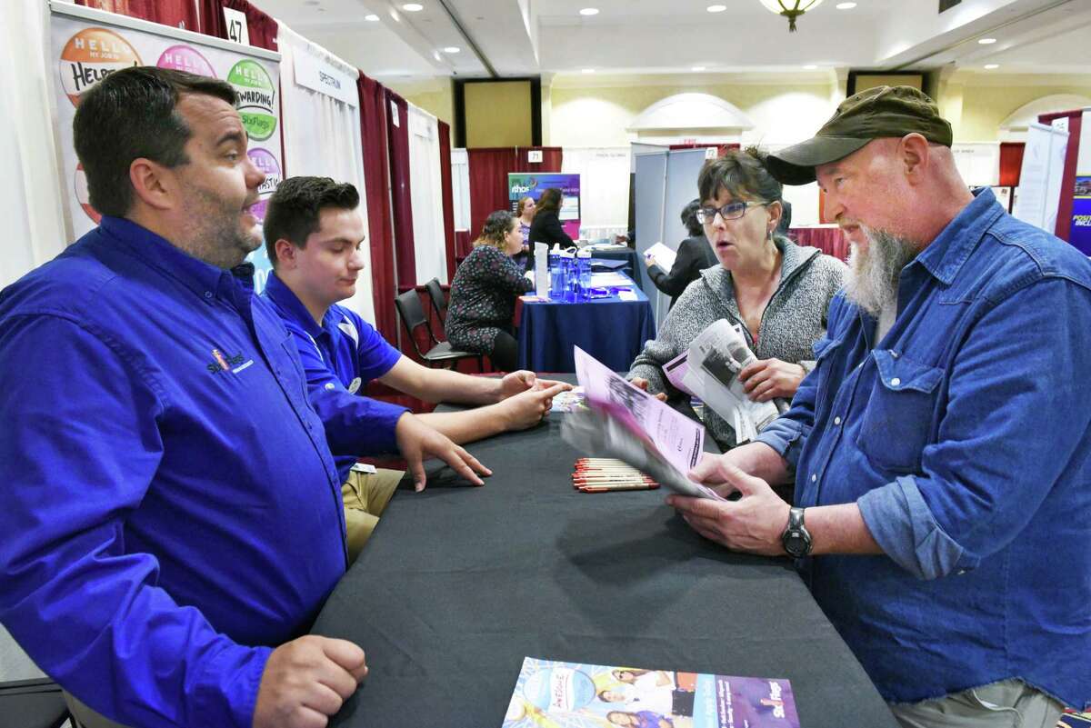 Six Flags America recruiters Bill Williams, left, and Wes Bessaw speak with job hunters Chris Mitchell of Colonie and Russell Brush, right, of Galway during the Times Union job fair Tuesday April 18, 2017 in Colonie, NY. (John Carl D'Annibale / Times Union)