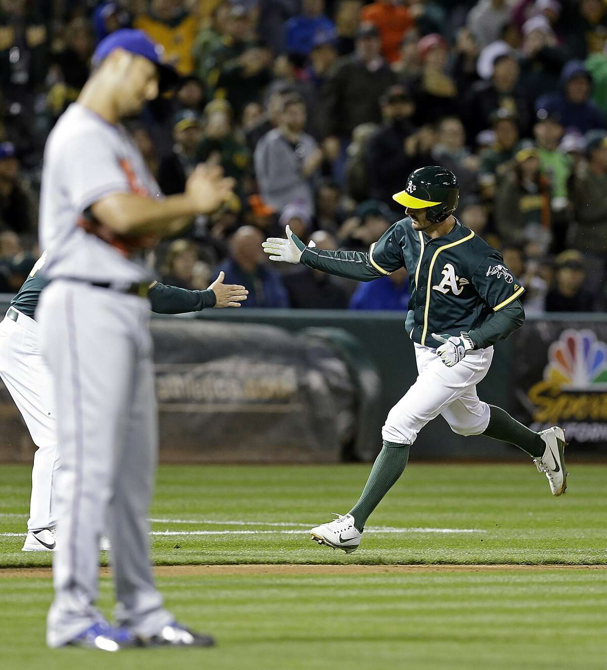 Oakland Athletics' Adam Rosales, right, celebrates as he rounds third base after hitting a two-run home run off Texas Rangers' Yu Darvish, foreground, during the sixth inning of a baseball game Tuesday, April 18, 2017, in Oakland, Calif. (AP Photo/Ben Margot)