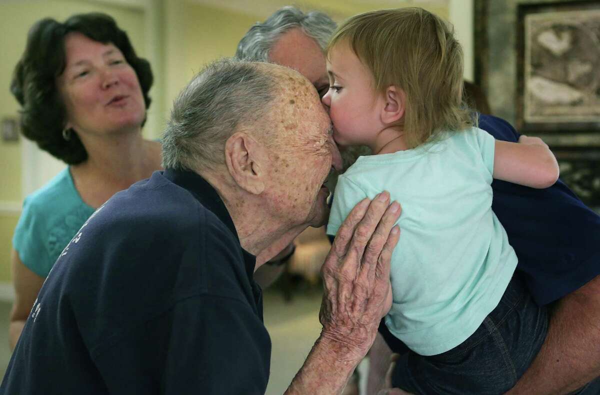 Eugene Ruf, a veteran of World War II, gets a kiss from his 22 month-old great grand daughter Grace Friedeck who is held by her grandfather Stanley Friedeck and grand mother Eileen Friedeck, left, celebrating his 108th birthday on Wednesday, April 19, 2017, at Brookdale Senior Living Solutions.