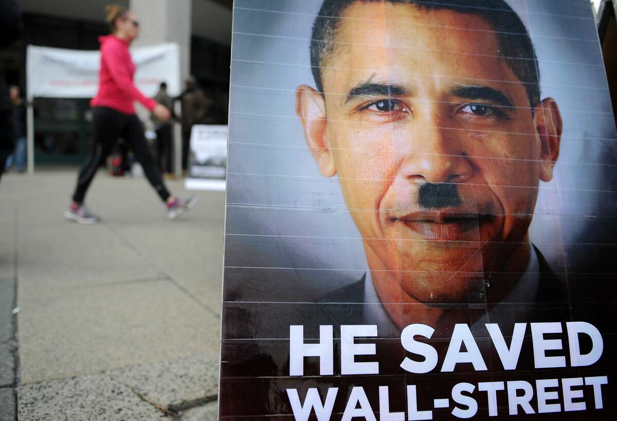 A woman walks past a poster depicting US President Barack Obama as Adolf Hitler during a demonstration by a group from LaRouche Political Action Committee near the White House in Washington, DC, on January 25, 2011 ahead of Obama's State of Union speech.