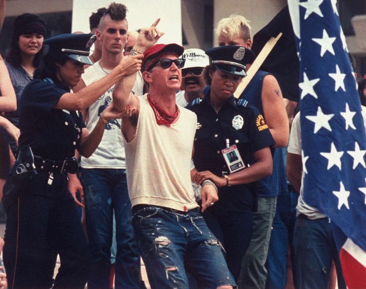 Police officers restrain radical Gregory Johnson after his flag-burning demonstration to express anger against Reagan policies during the 1984 Republican National Convention in Dallas.