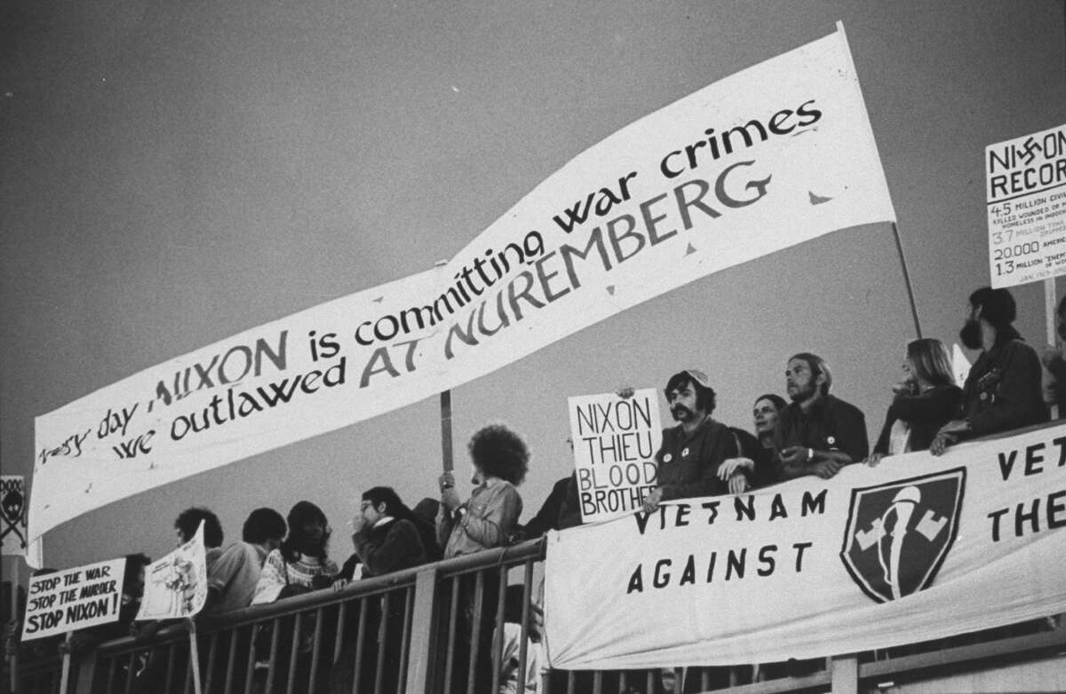 Anti-war protestors, including some Vietnam Veterans Against the War, holding banners denouncing the general war effort and President Richard Nixon specifically outside hotel where Nixon is holding fund raising dinner.