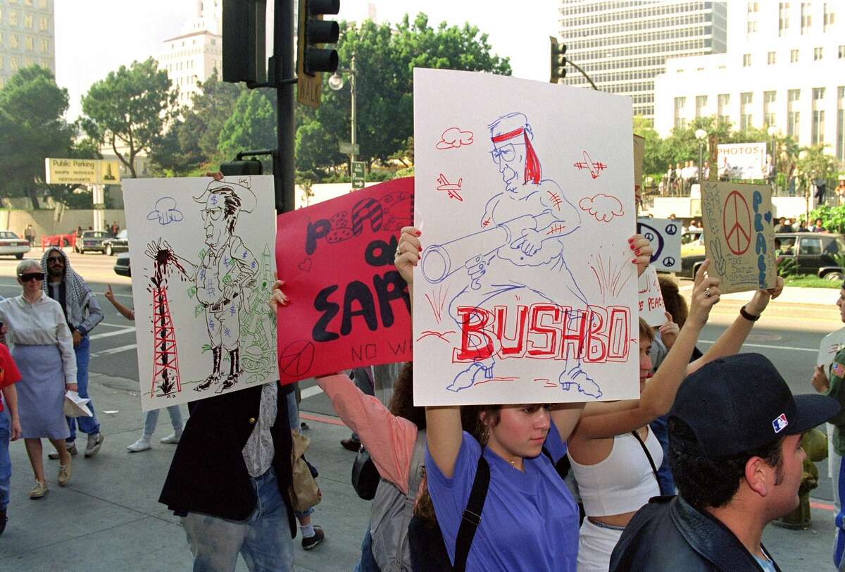 A protester holds up a placard with a drawing of US President George Bush represented as "Rambo" during an anti-Gulf war demonstration, January 15, 1991, against the US involvement in the Persian Gulf War, in Los Angeles.
