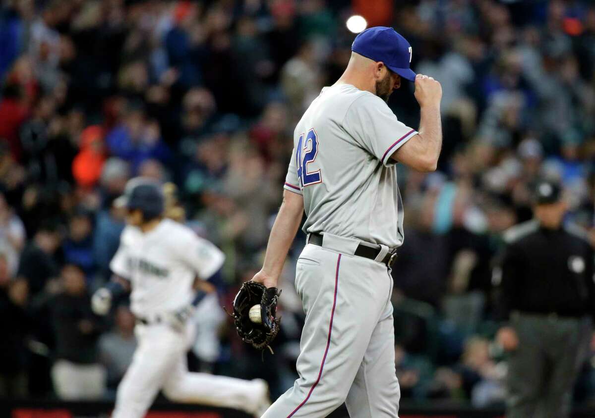 Texas Rangers relief pitcher Mike Hauschild, right, turns away as Seattle Mariners' Taylor Motter rounds the bases behind on a three-run home run during the sixth inning of a baseball game Saturday, April 15, 2017, in Seattle. The Mariners won 5-0. (AP Photo/Elaine Thompson)