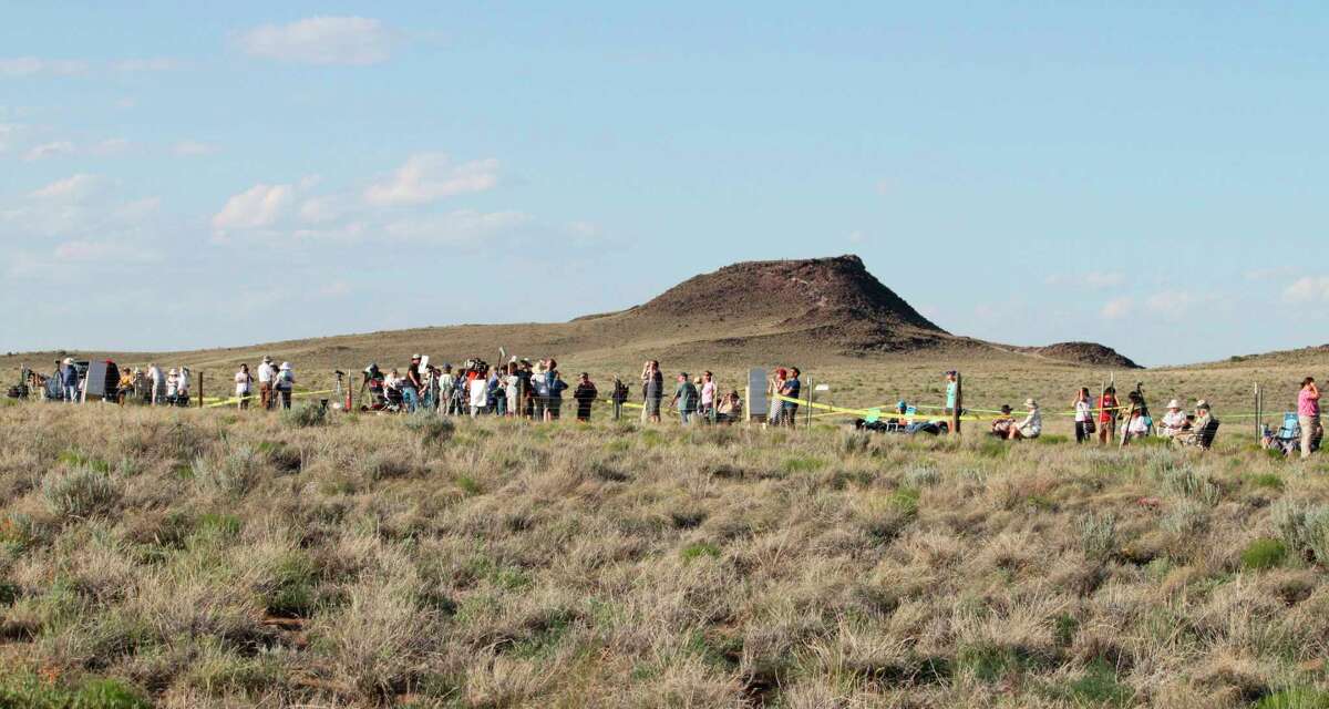 FILE - In this May 20, 2012 file photo, people line the fence line at the Petroglyph National Monument near Albuquerque, N.M., to watch the annular solar eclipse.