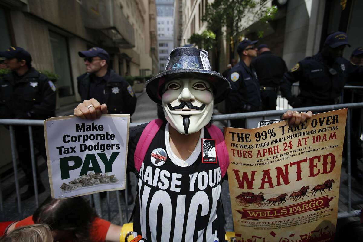 Christy Wong of San Jose holds signs as she protests with others outside the Merchants Exchange Building where the Wells Fargo Shareholders' Meeting is held on Tuesday, April 24, 2012 in San Francisco, Calif.