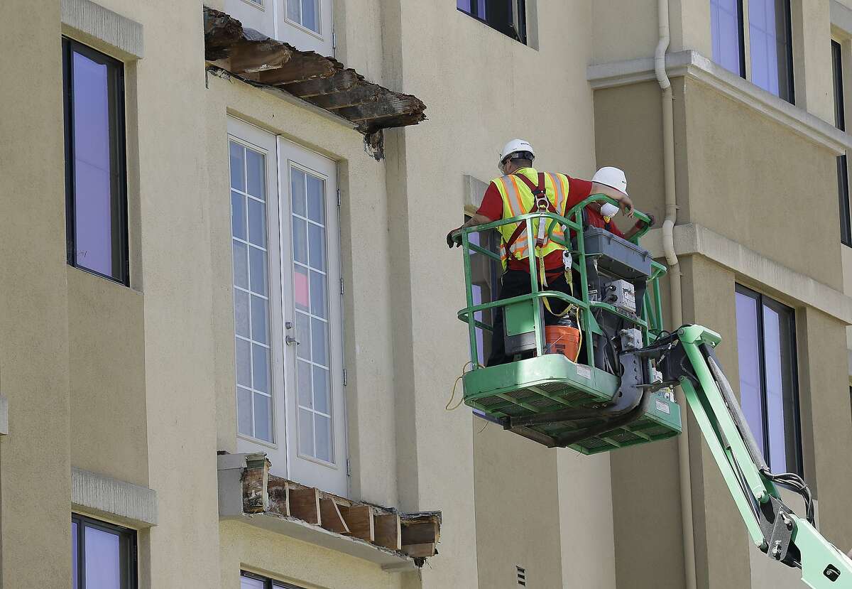A crew work on the remaining wood of an apartment building balcony that collapsed, top, and one that was removed, below, in Berkeley, Calif., Thursday, June 18, 2015. A balcony broke loose from an apartment building during a 21st birthday party early Tuesday, killing several and seriously injuring several others. (AP Photo/Jeff Chiu)