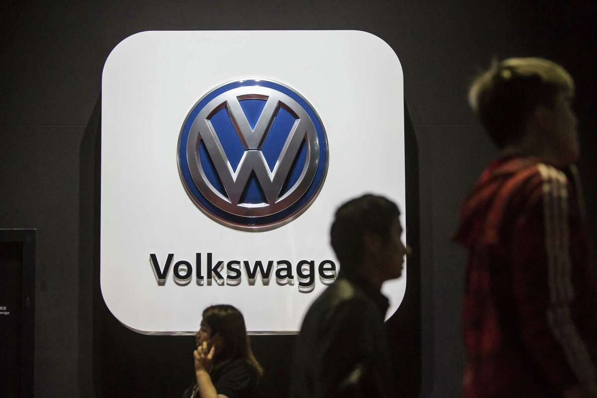 People walk past signage for Volkswagen AG in the company booth at the Auto Shanghai 2017 vehicle show in Shanghai, China, on Thursday, April 20, 2017. Auto Shanghai runs through to April 28. Photographer: Qilai Shen/Bloomberg ORG XMIT: 700037383
