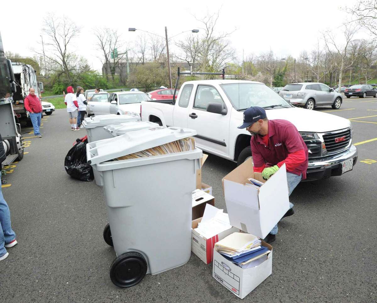 At right, Santaguida Sanitation worker Juan Vazquez stacks boxes of paper for shredding during the annual Paper Shredding Day in the Island Beach parking lot in Greenwich, Conn., Saturday, April 22, 2017. According to Mary Hull, president of Greenwich Green & Clean, an organizer of the event along with the Greenwich Recycling Advisory Board, said "Wow great turn out. Great Earth Day event. Lots of smiles for recycling." The event was sponsored by First Bank of Greenwich and Santaguida Sanitation and was staffed with teenagers from the Boys and Girls Club and volunteers from various town organizations.