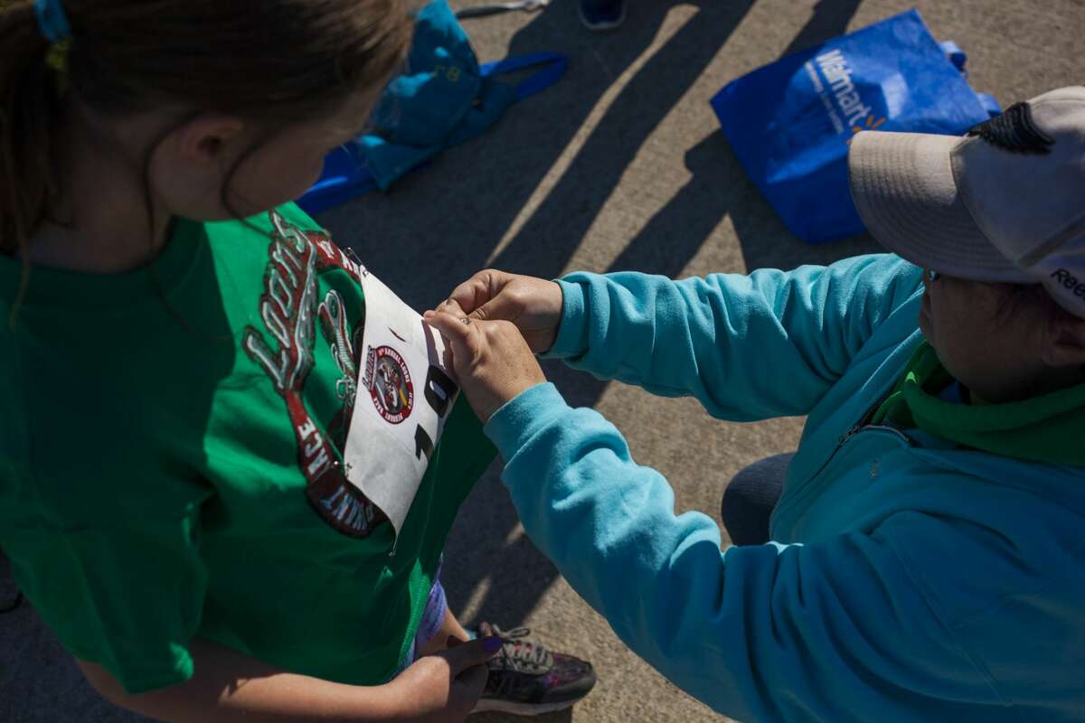 JOSIE NORRIS | for the Daily News Mackenzie Burger, 12, of Mount Pleasant looks down as her mother, Melanie Burger pins Mackenzie's bib onto her t-shirt before competing in the Loons Pennant Race Saturday morning in Midland.