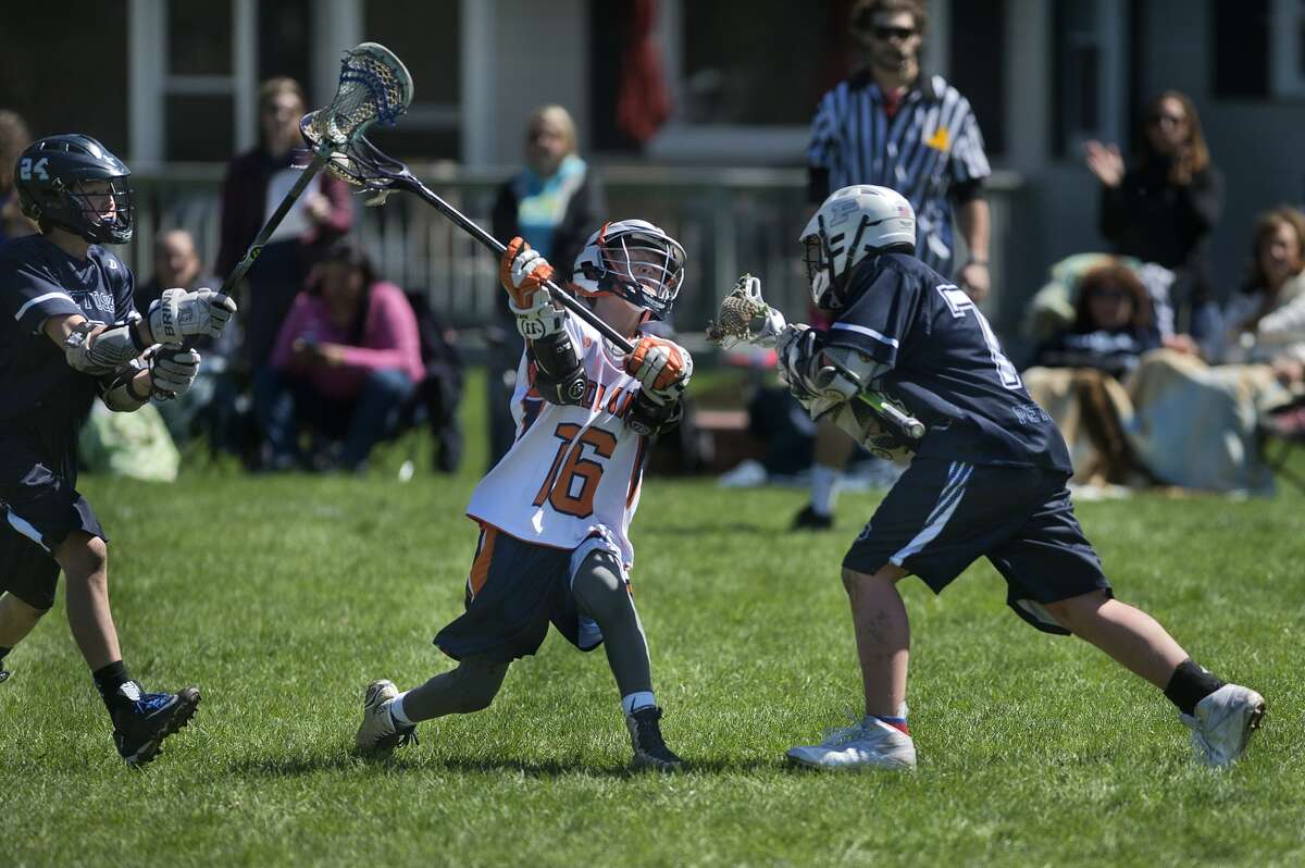 BRITTNEY LOHMILLER | blohmiller@mdn.net Petoskey's Tyler LaFaive, left, and Seth Doe-Nimphie defend Midland Orange 14UA's Cal Stearns during the Midland Lacrosse Club's Honor the Game tournament Saturday at Jefferson Middle School. Midland defeated Petoskey 11-3.
