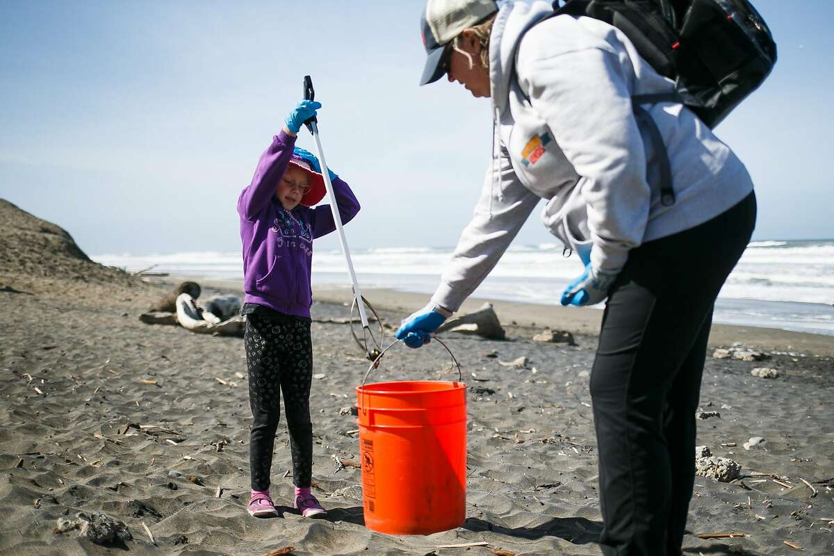 Ellen Ashley holds the bucket as Grace Coachman, 6, picks up a water bottle during the Surfrider Foundation's annual beach clean-up event at Ocean Beach in San Francisco, Calif. Sunday, April 23, 2017.