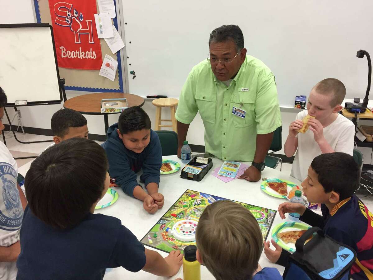 Lion Pete Martinez of the Conroe Noon Lions Club supervises a game of 'Life' with a group of 3rd graders during their FUN FRIDAY event at the club's adopted school of Reaves Elementary.