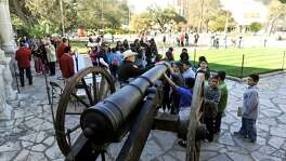 Children look over a replica of the 18-pound cannon fired in response to Gen. Santa Anna's demand for surrender at the Alamo.