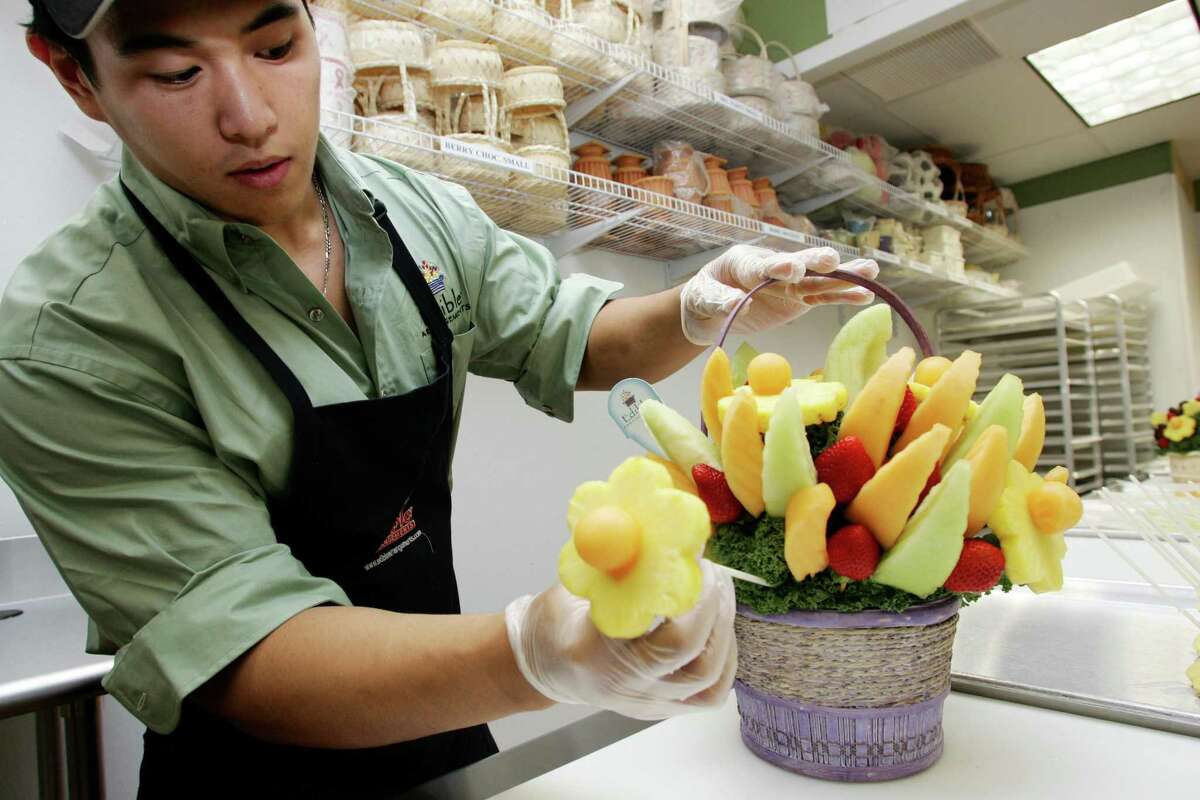 A worker in Mamaroneck, N.Y., demonstrates how to create a holiday centerpiece using fruits for Edible Arrangements.