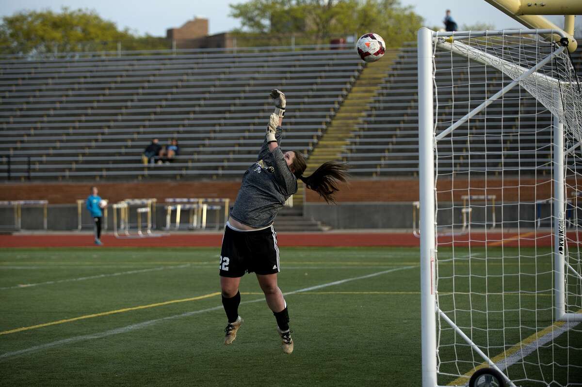 Bay City Western's goalie Molly Mantei jumps to deflect a shot on the goal in the first half of the girls soccer game Monday evening against Midland High.