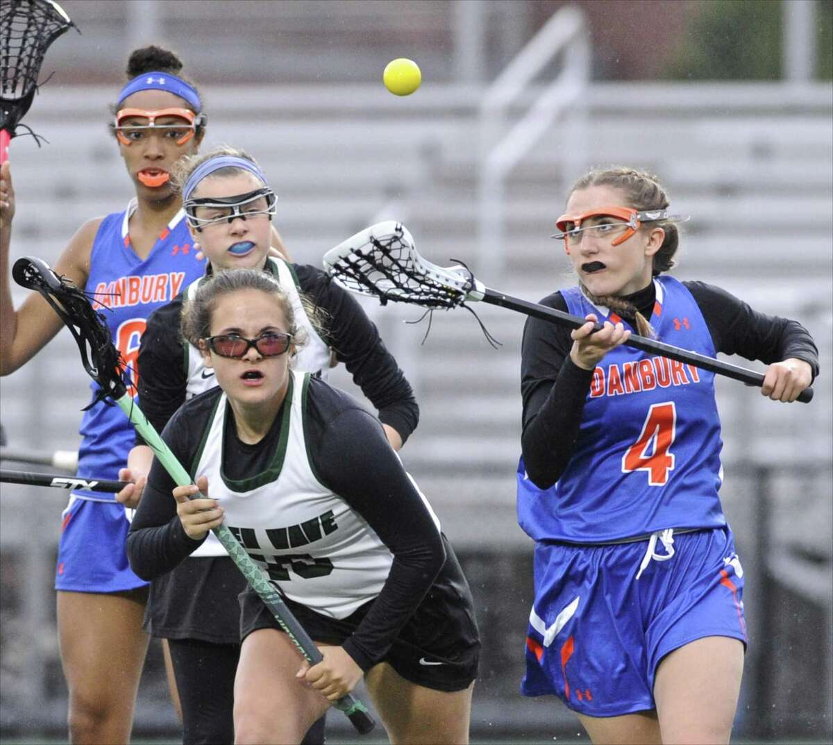 Danbury's Joelene Heffern (4) reaches for the ball in front of New Milford's Julia Venezia (10 in the girls lacrosse game between Danbury and New Milford high schools, on Tuesday afternoon, April 25, 2017, at New Milford High School, in New Milford, Conn. New Milford's Kelly Lourenco (16) and Danbury's Ciara Tonic (6) are behind the play.