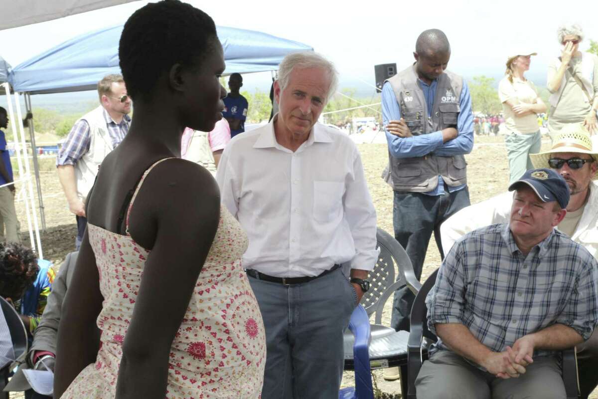 In this photo taken on Friday, April 14, 2017, U.S Senators Bob Corker, center, and Chris Coons, right, speak with a South Sudanese refugee during a group discussion at the Bidi Bidi refugee settlement in northern Uganda. In a political climate dominated by President Donald Trump's slogan of "America First," two U.S. senators are proposing making American food aid more efficient after meeting with victims of South Sudan's famine and civil war. After visiting the world's largest refugee settlement in northern Uganda, Democratic Sen. Chris Coons of Delaware told The Associated Press that the U.S. "can deliver more food aid at less cost" through foreign food aid reform. (AP/Photo/Justin Lynch)