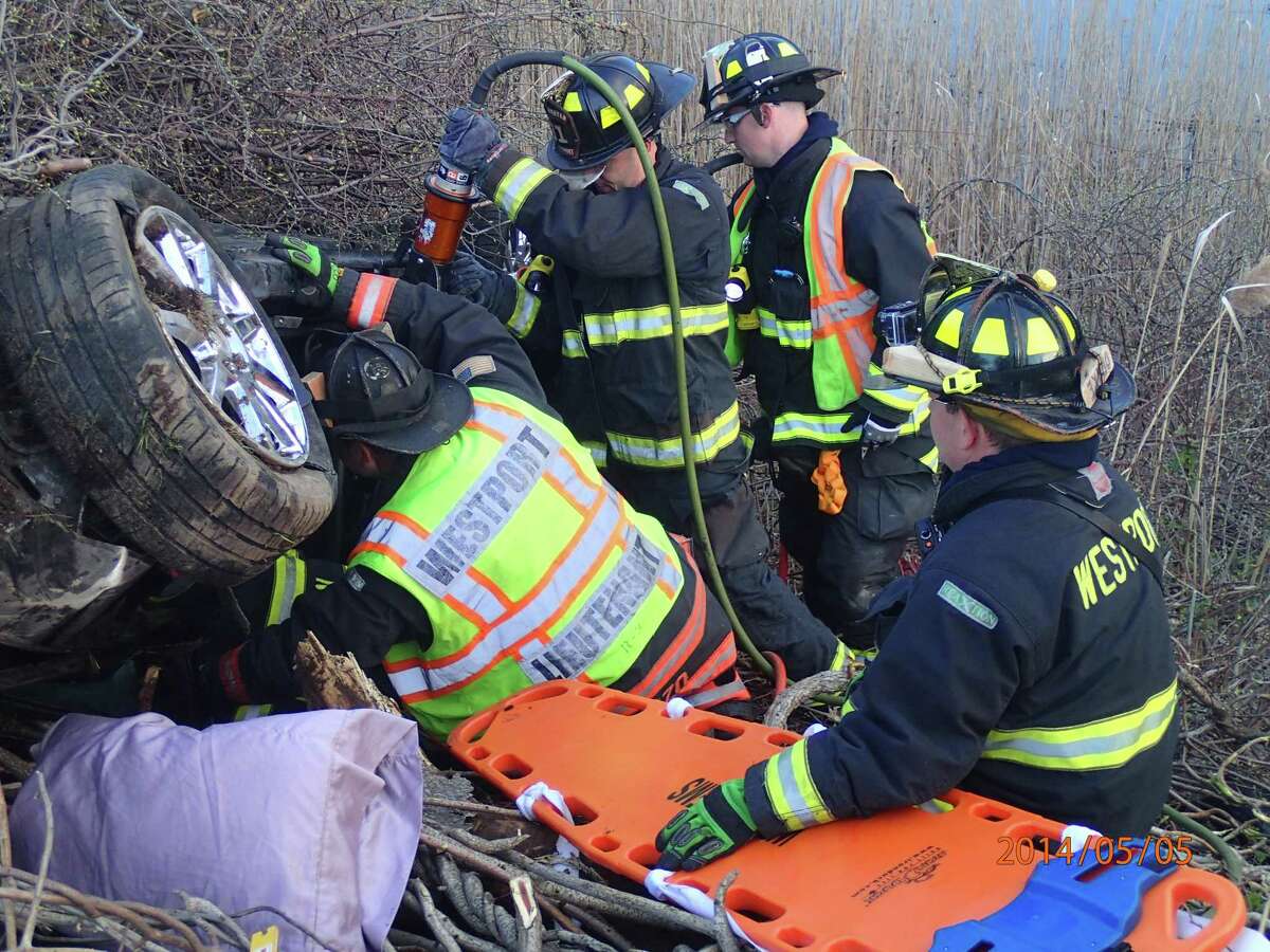 Westport firefighters extricate two people from a vehicle that overturned down on an embankment after a crash early Monday May 5, 2014 on Interstate 95 between southbound Exits 18 and 17 in Conn.
