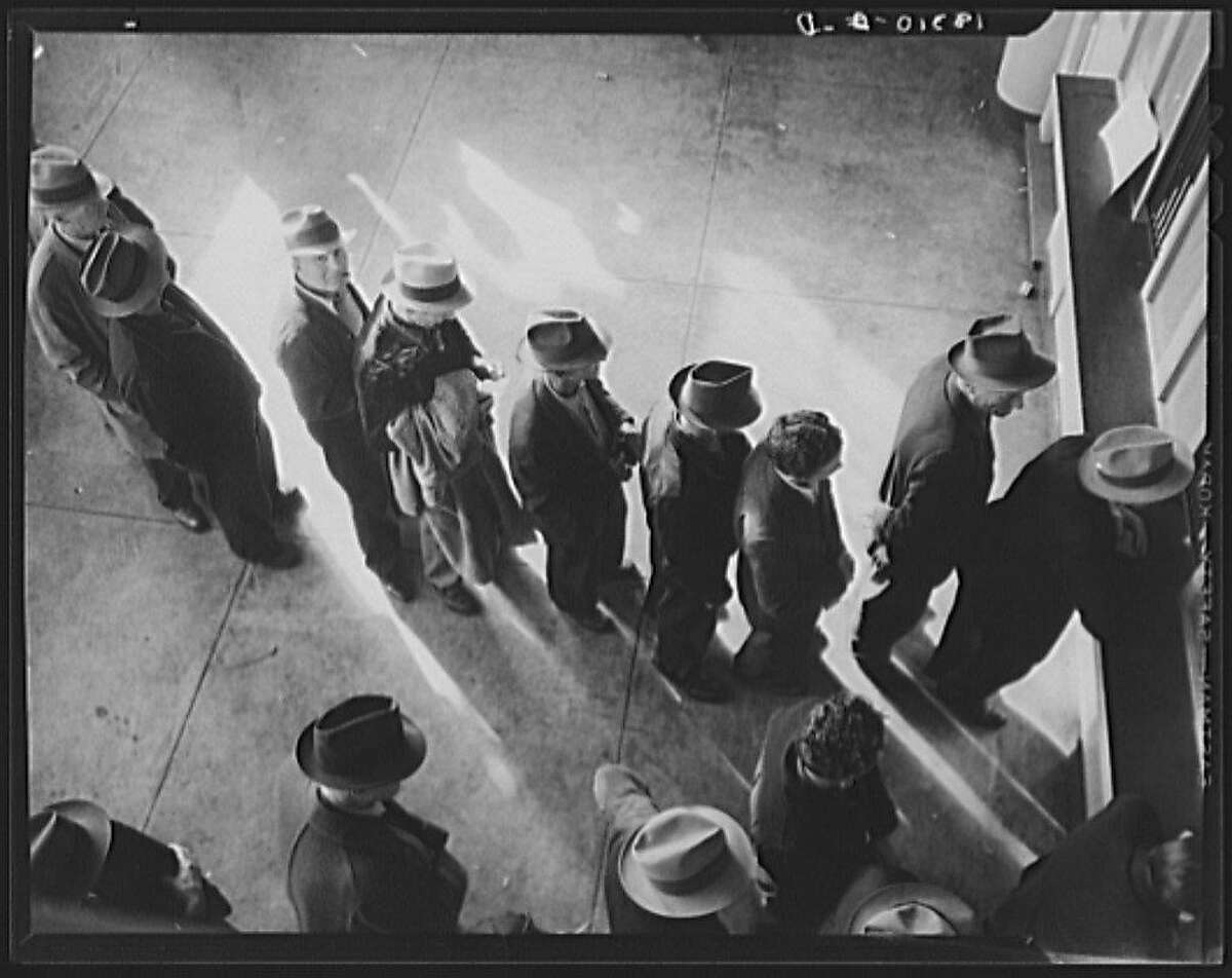 Unemployment benefits aid begins. Line of men inside a division office of the State Employment Service office at San Francisco, California, waiting to register for benefits on one of the first days the office was open. They will receive from six to fifteen dollars per week for up to sixteen weeks. Coincidental with the announcement that the federal unemployment census showed close to ten million persons out of work, twenty-two states begin paying unemployment compensation - January 1938.