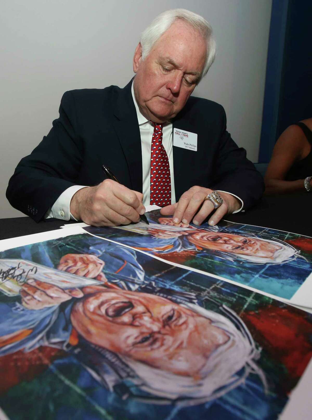 Wade Phillips autographs a poster of his coaching days in the NFL with the Denver Broncos Tuesday Feb. 21, 2017, in Waco, Texas before being inducted into the Texas Sports Hall of Fame class of 2017. (Jerry Larson/Waco Tribune Herald via AP)
