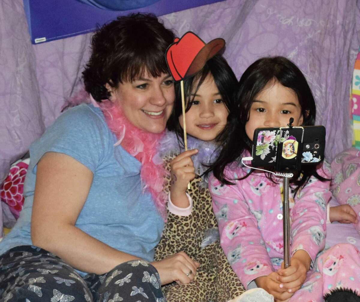 Susanna Telford and her daughters, Emme Lim, 6, and Kendall Lim, 8, capture a lighthearted moment together at the selfie station, one of several stations set up at the pajama-themed party.