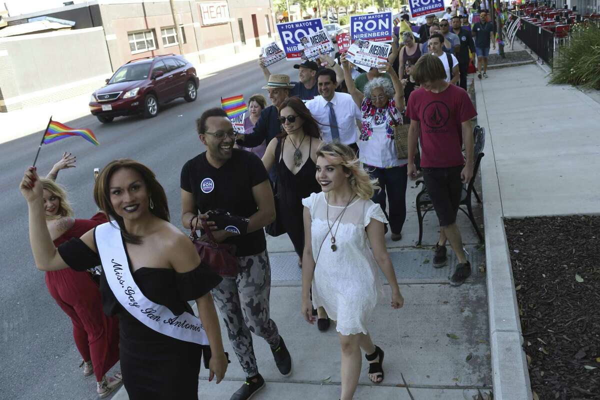 Miss Gay San Antonio Aaron Andrews, and Clark High School senior Sloan Martin, 18, center right in white, lead the March for Mayor on Main, Wednesday, April 26, 2017. Martin organized the march to bring awareness to the LGBTQ community and increase the LGTBQ vote. Of the three top candidates, Mayor Ivy Taylor decline the invitation, Ron Nirenberg had a prior engagement but sent staff. Only Manuel Medina attended. The group gathered at Luther's Cafe on North Main Street and marched to the William R. Sinkin Eco Center polling site a few blocks away where several, including Martin, voted.