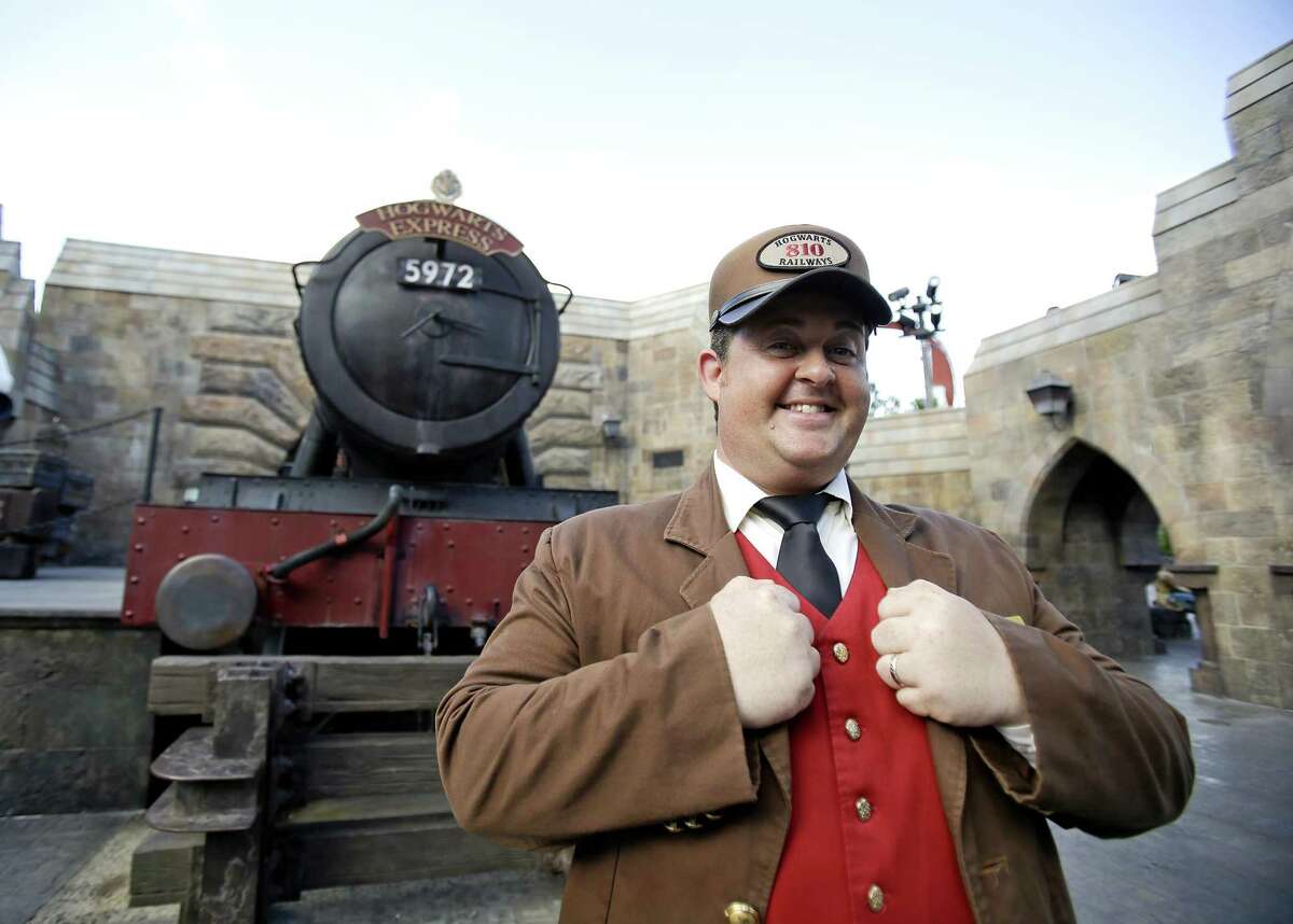 A station agent greets guests in front of the Hogwarts Express train at the Wizarding World of Harry Potter at Universal Studios in Orlando, Fla. Comcast has spent billions of dollars refurbishing and expanding its park empire, growing into Asia and adding rides and attractions to its California and Florida destinations.