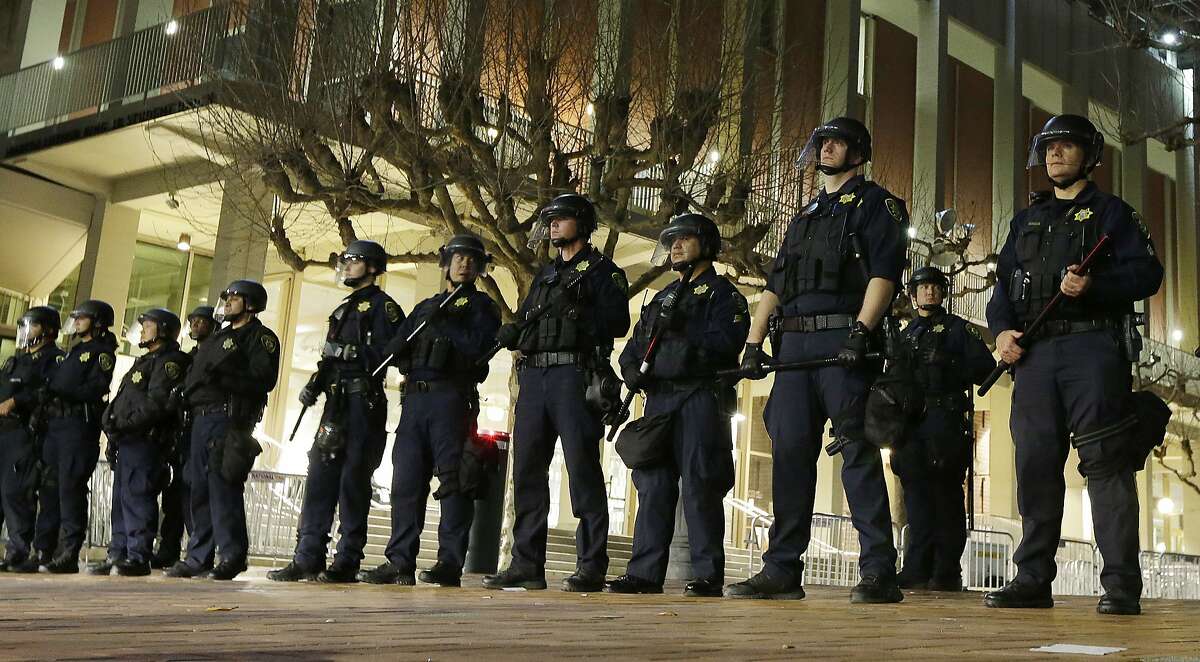 FILE - In this Feb. 1, 2017 file photo, University of California, Berkeley police guard the building where Breitbart News editor Milo Yiannopoulos was to speak. The campus is bracing for a showdown next week, when the conservative provocateur Ann Coulter has vowed to speak in defiance of the university's wishes. Officials, police and the campus Republicans who invited Coulter, say there are valid concerns for violence in what is being called an ongoing "Battle of Berkeley." (AP Photo/Ben Margot, File)