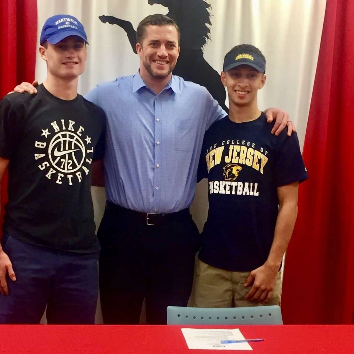 J.J. Conway. left, and Marcel Parsons, right stand next to Warde boys basketball coach Ryan Swaller after both signed letters of intent to continue playing basketball in college. Six other Mustangs student-athletes also signed collegiate LOI.