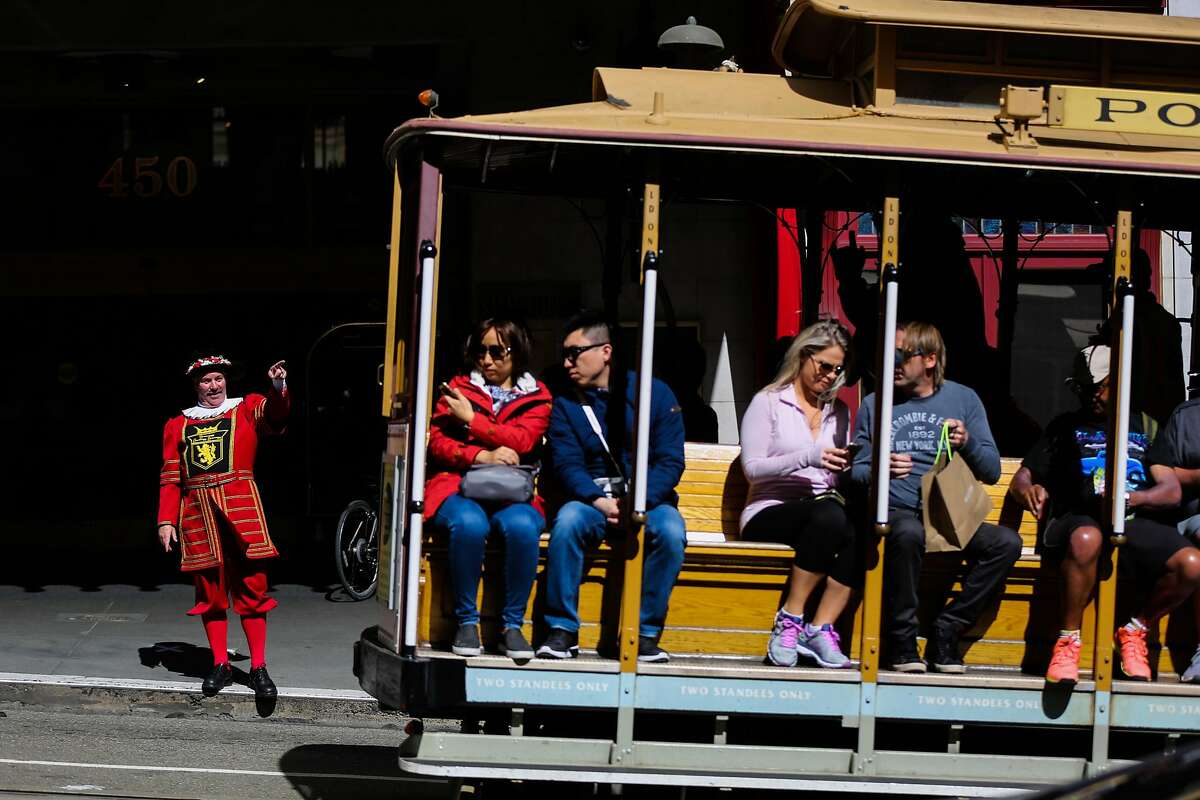 Sir Francis Drake hotel doorman Tom Sweeney greets a cable car as it rides past the hotel on Powell Street in San Francisco, California, on Thursday, April 27, 2017.