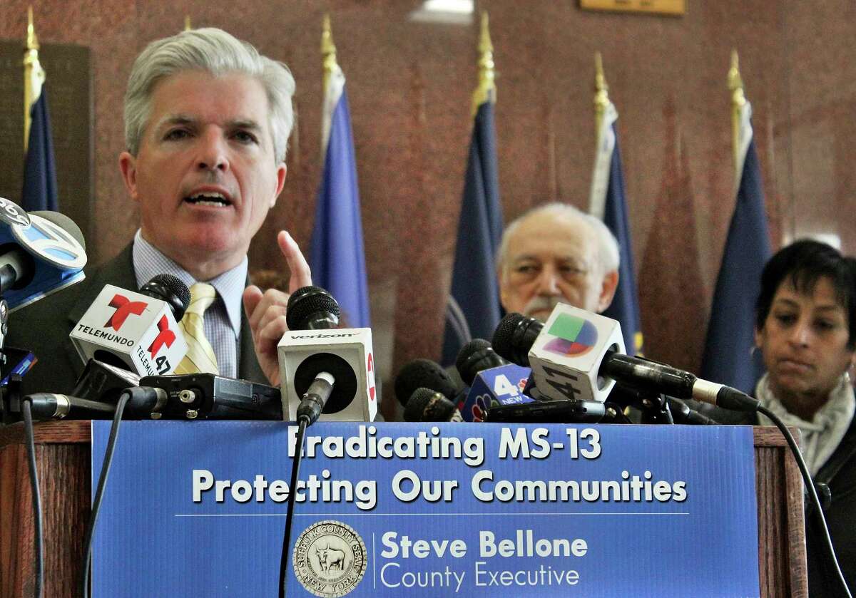 In this Monday, April 24, 2017 photo, Suffolk County Executive Steve Bellone speaks at a press conference in Hauppauge, N.Y., where he vowed to take action against the MS-13 street gang. MS-13 has been blamed for a trail of nearly a dozen corpses of mostly young people discovered in woods and vacant lots in Brentwood and neighboring Central Islip since the start of the school year. At right is Evelyn Rodriquez whose daughter, Kayla Cuevas, was killed in September 2016 in what prosecutors said was one of those killings. Central Islip School District Superintendent Dr. Howard Koenig is at center. (AP Photo/Frank Eltman) ORG XMIT: NYR206