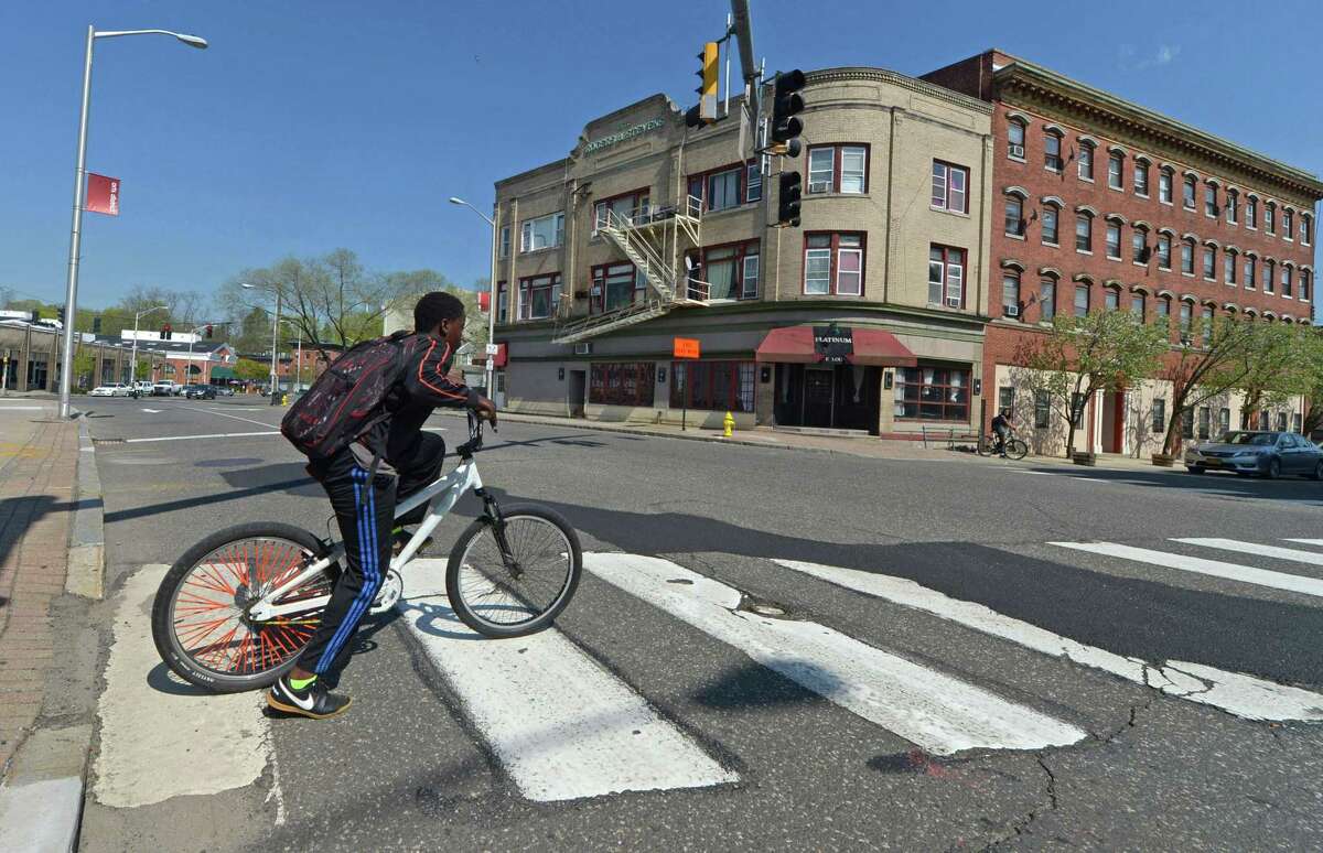 A boy on a bicycle looks to cross Wall Street at Commerce Street Friday, April 28, 2017, in Norwalk, Conn. With Wall Street Theater recently opened, Head of the Harbor South nearing completion, a roof-top bar planned and a nearly completed master plan for Irving C. Freese Park, the long-planned but frustrated effort to bring the neighborhood back from the devestating 1955 flood reached critical mass.